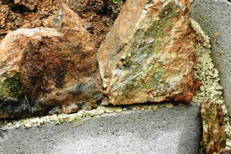 Erste Steine der Trockenmauer auf das Streifenfundament setzen